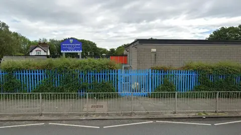 Google The exterior of Riverside Primary School in Seacombe with blue fencing and a blue sign 