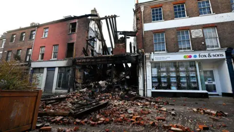 Getty Images/Finnbarr Webster A general view of the scene of the fire, on December 09, 2024 in Dorchester, England, with bricks spilling out into the street. 