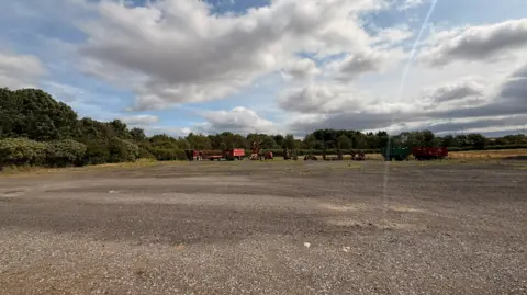 Tania Tallon A pebbled land at Offeton Grange Farm with farming machinery and trees in the distance.