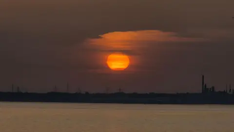 stacey johns A large orange sun in the sky above the Solent.