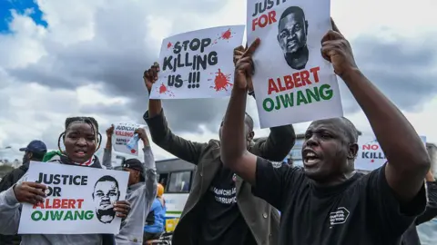 Protesters holding up posters which say "Justice for Albert Ojwang" and "stop killing us".