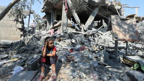A Palestinian child sits amid the rubble of a building destroyed in a reported Israeli air strike in Nuseirat refugee camp, in central Gaza (9 July 2024)
