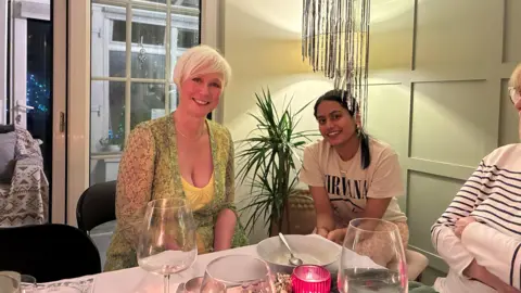 Two women are sitting at a table and smiling at the camera