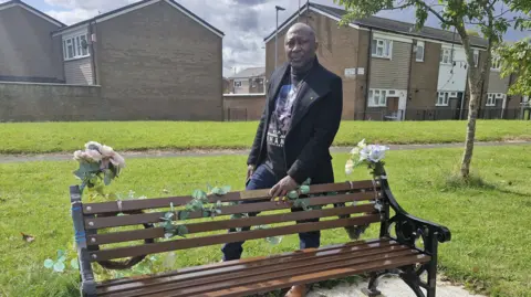 Mr. Shani stands behind Nathaniel's bench