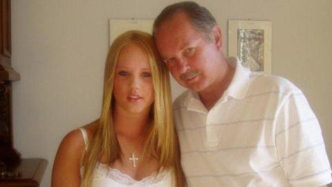 Kiri, aged 18, standing next to her father