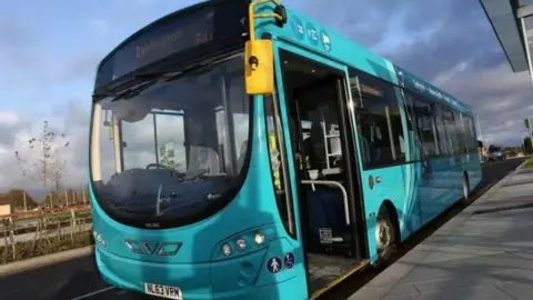 A light blue Arriva single-decker bus. It is empty and the doors are open.