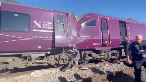 The two carriages that collided are seen in this picture - a door is hanging off one, while the front of the other is crumpled. A police officer can be seen on tracks in the foreground