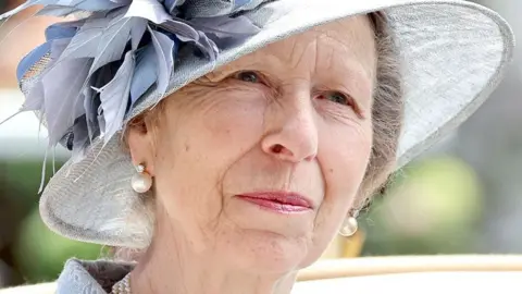 The Princess Royal, Princess Anne, in a blueish-grey hat with decorative leaves in the same colour and large pearl earrings