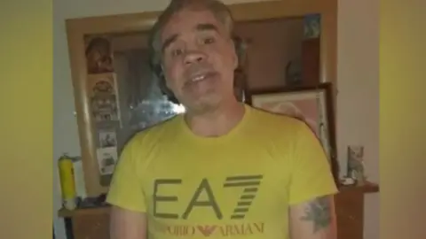 Family Tony Browne, wearing a yellow t-shirt, standing centre of the photo