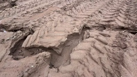 A close up of a brown muddy field with a large crack running from left to right