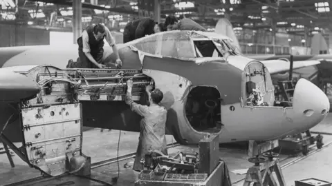 Getty Images A black and white photo of men building a plane.