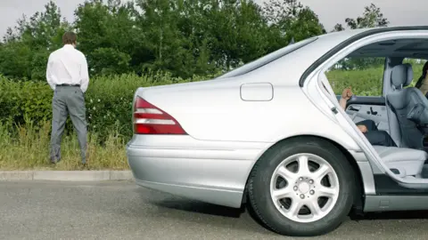 Stock photo of a man urinating at the side of the road