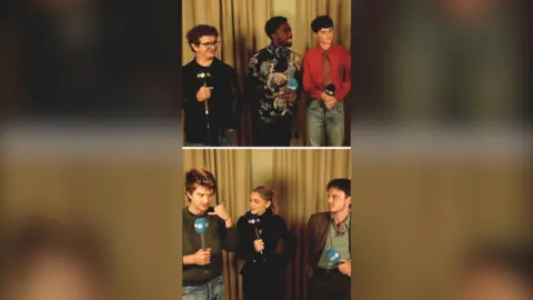 Cast of Stranger Things standing in front of a gold curtain