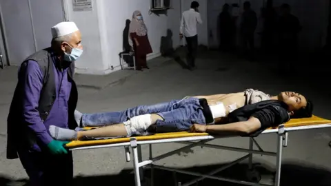 Reuters An Afghan man wheels an injured man in a hospital after a suicide bombing in Kabul, Afghanistan 24 October 2020