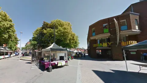 Google A row of white tents with stall holders selling crafts and products