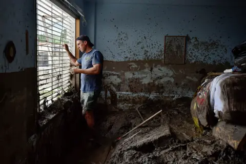 GABY ORAA / Reuters Juan Figalo looks out the window of what was left of his bedroom in the neighbourhood of El Castano, in Maracay, Aragua state, Venezuela, 18 October 2022