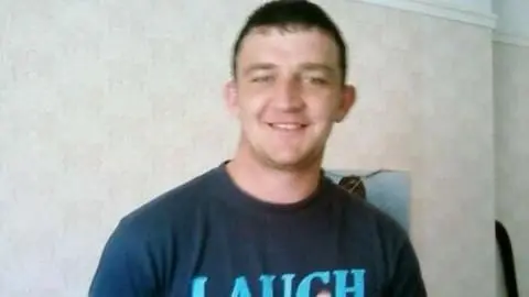 James Brogan wearing a navy t-shirt and smiling at the camera.