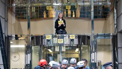 XR Protest: Gail Bradbrook on top of the government building's entrance