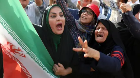 An Iranian woman holding a national flag shouts slogans during an anti-US and anti-Israel demonstration in Tehran