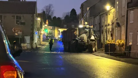 BBC/Luke Manterfield A tractor behind a police cordon on a street. It can be seen to have mounted the footpath
