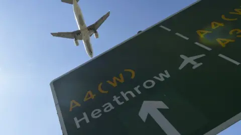 EPA Plane flies over Heathrow road sign