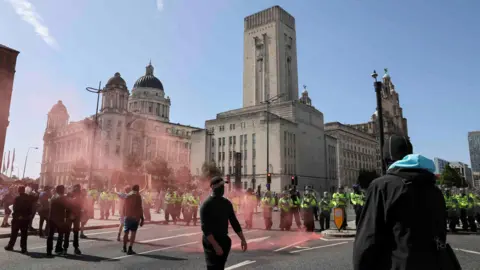 Reuters people clad in black and police officers on the Pier Head