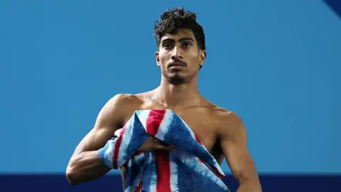 Getty Images Kyle with a Team GB towel, after coming out from the water. The background is blue.