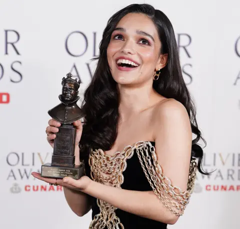 Ian West / PA Wire Picture of Rachel Zegler smiling and holding her Olivier award in front of a white board with the text 'Olivier awards' on it.