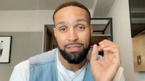BBC Ashley Banjo doing an OK sign with his hands to a camera mid-speech