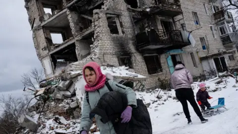 Getty Images Family outside destroyed building in Izyum