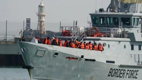 PA Media A group of people thought to be migrants are brought ashore in Dover on a Border Force vessel