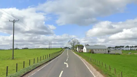 A road between two fields with green grass