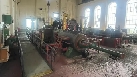 Mike Johnson A large metal engine in the engine shed of Haig Colliery in Whitehaven. Arched windows run down the side of the hall and a viewing platform stands next to the engine.