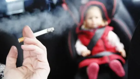 PA Smoking cigarette in a car with a child size doll in the back seat