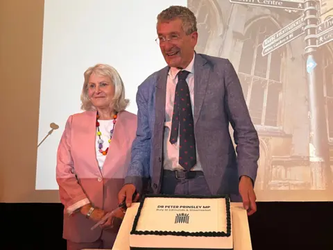 Contributed The MP, standing next to his wife, in front of a cake to celebrate the new space. 