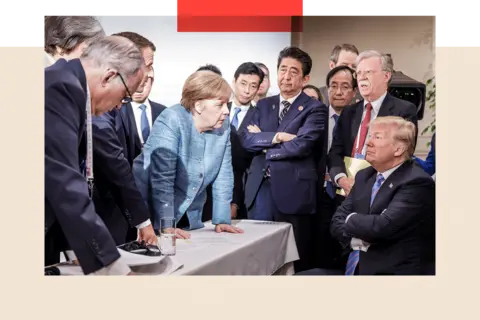 Getty Images Former German Chancellor Angela Merkel deliberates with Donald Trump during the G7 summit, arsenic  helium  beryllium   with his arms folded