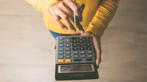 A woman holding a pen and using a calculator