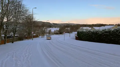 Travel warnings as snow and ice impact northern Scotland 8 Car travelling along a road covered in fresh snow