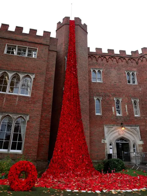 Reuters More than 15,000 poppies - knitted by the Secret Society of Hertford Crafters as well as schoolchildren and people in care homes, pour down Hertford Castle