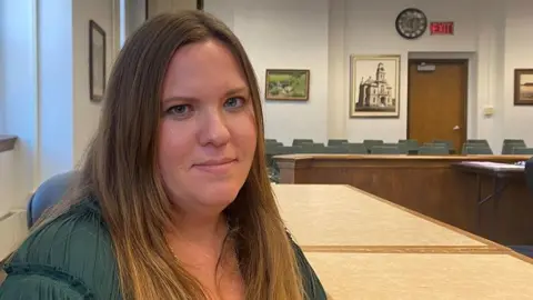 BBC / Mike Wendling A woman in a green dress in a community office looks into the camera