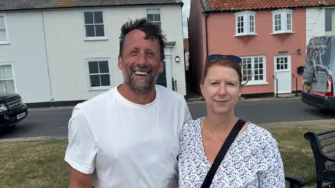 George King/BBC A head and shoulders image of Julie Lucas and her husband (who is pictured on the left). They are standing next to each other and looking into the camera.