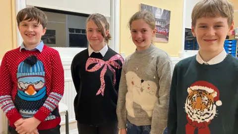 Four young people wearing festive jumpers
