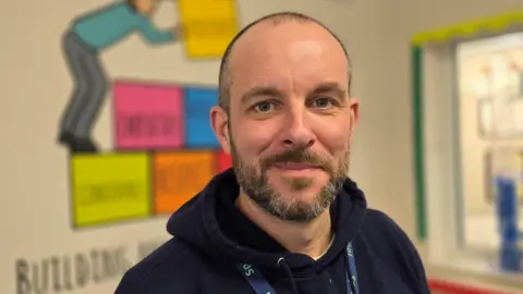 Paul Moseley/BBC Connor Gateley is smiling at the camera, wearing a dark navy hoodie and school lanyard.