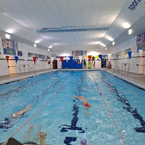 A swimming pool with swimmers in it going up and down.