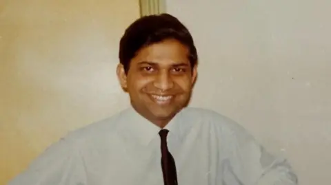Rotherham NHS Foundation Trust A man with black hair, a white shirt and black tie smiles at the camera