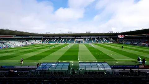 A view of the Home Park stadium. The pitch is green and you can see the stands surrounding the grounds. 