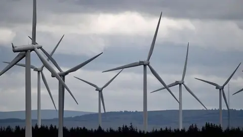 wind turbines in a field with hills in the background