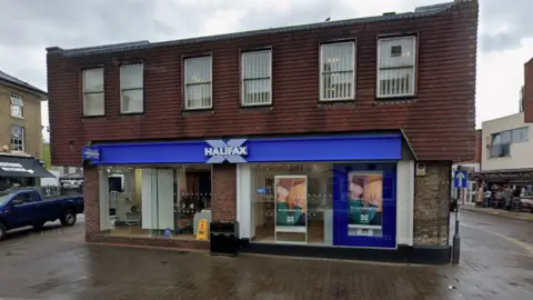 A detached Halifax bank building in a town centre surrounded by roads