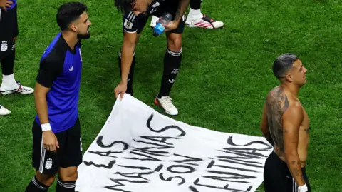 Argentina's Nicolas Gonzalez looks at a banner displaying a message referencing the Falkland Islands 
