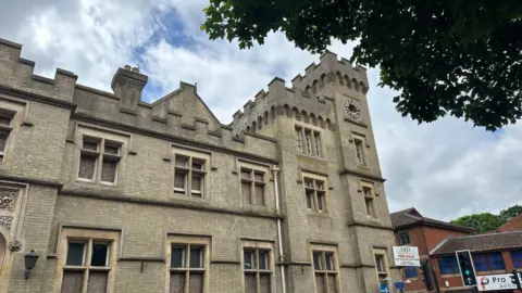 Alice Cunningham/BBC Another view of part of County Hall. Windows can be seen spanning three storeys while a clocktower can be seen at the end of the building.